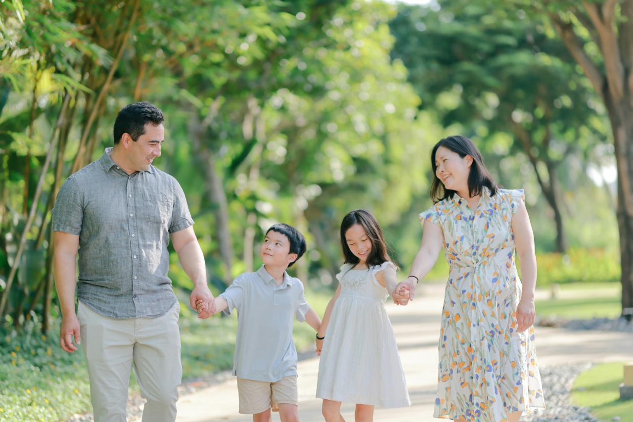 A family walks hand-in-hand on a park path.