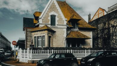 A house with a white picket fence and cars parked in front of it